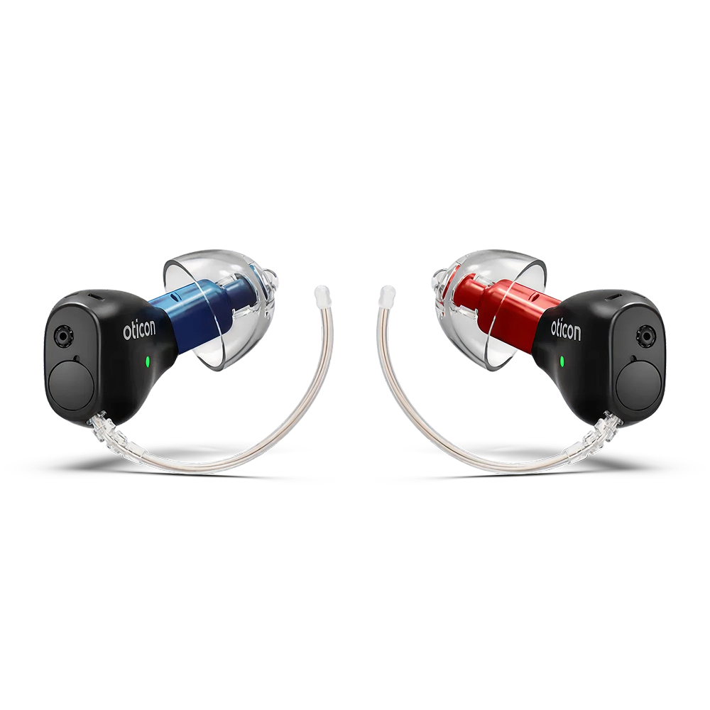 Two black Oticon Zeal™ 1 hearing aids are shown side by side. The left has a blue accent, the right a red one. Both feature clear earpieces and thin transparent tubes for fitting in the ear.