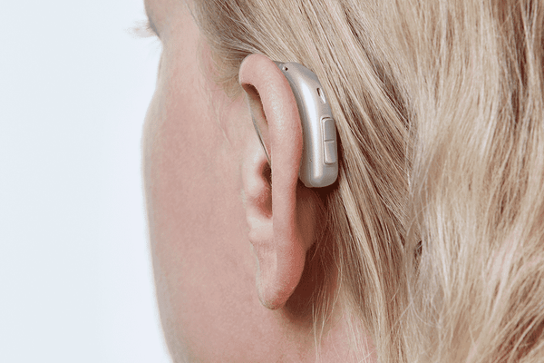 Oticon More hearing aid, model miniRITE R, Light Grey colour, photo taken from behind from a 45° angle, Close-up On Ear, Woman Hearing Aids with Auzen unlimited service